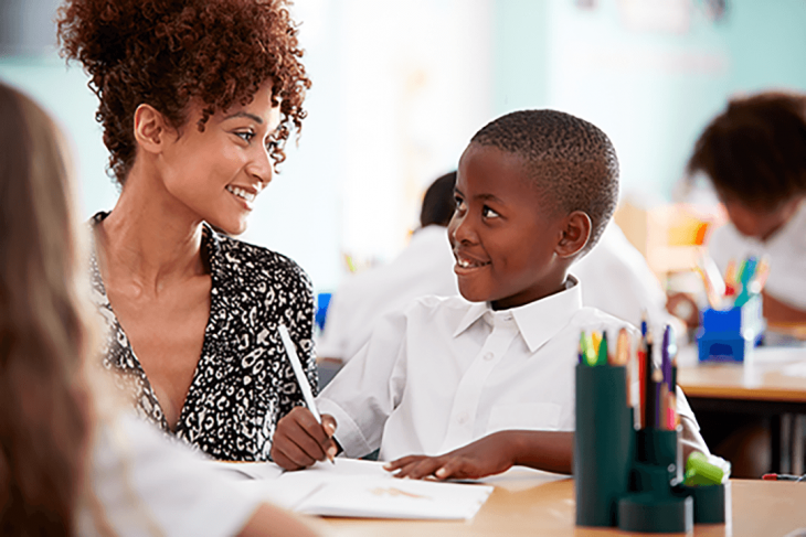 Teacher helping smiling student in Africa