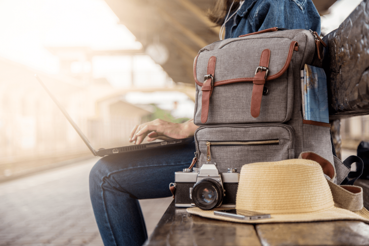 traveler sitting at train station studying TEFL certification online on laptop