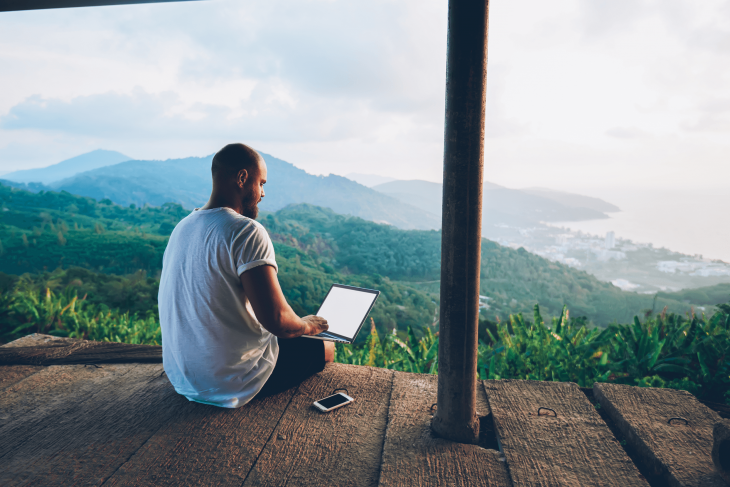 man on laptop studying TEFL certification online while traveling