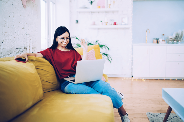 woman waving at laptop camera while teaching English online