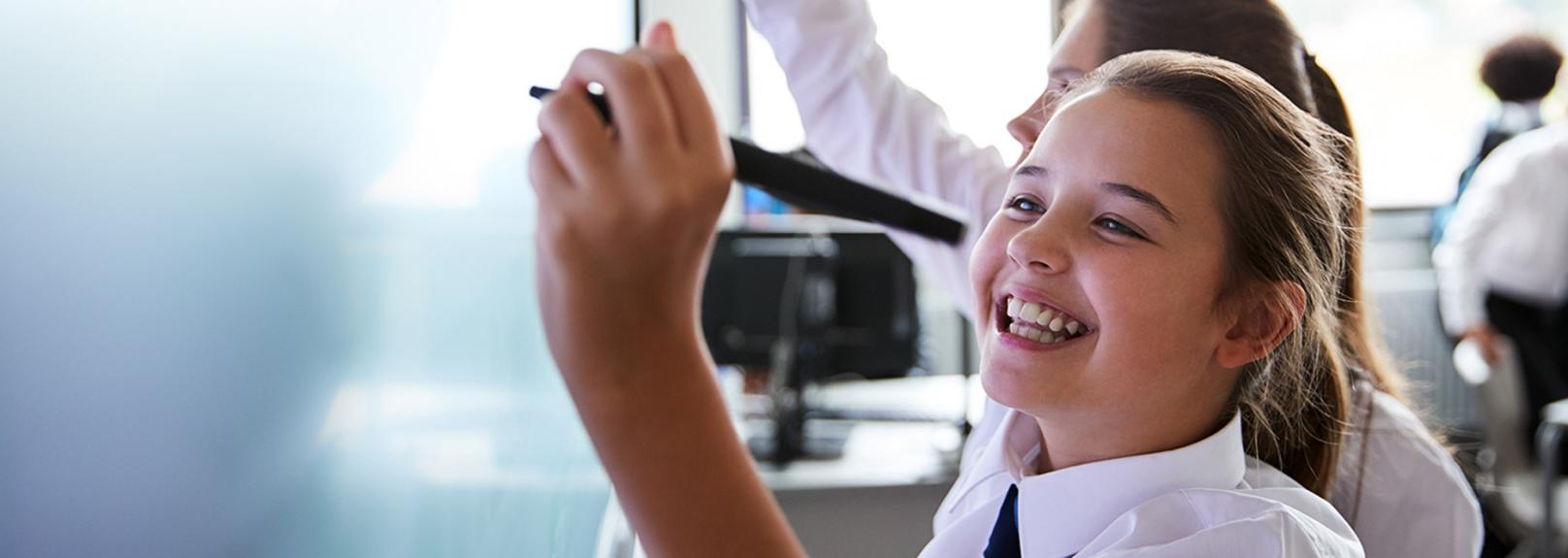 An overseas teaching recruitment agency that takes care of your recruitment Young students in uniform, smiling and writing on a whiteboard - overseas teaching recruitment agency