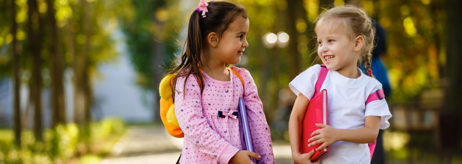Find the right teachers for your young learners Two young girls wearing backpacks and carrying school books - early childhood education recruitment agency