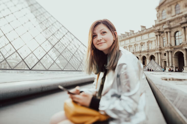  recent college graduate in paris sitting in front of the louvre and teaching english abroad with a bachelor’s degree