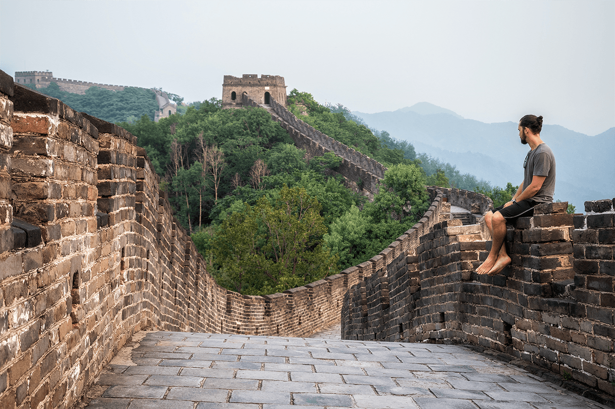 young traveller sitting on Great Wall of China