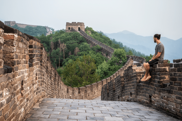 person sitting at the great wall of china - how to travel the world and make money