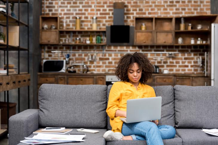 woman sitting on couch on laptop - productive things to do at home during covid-19