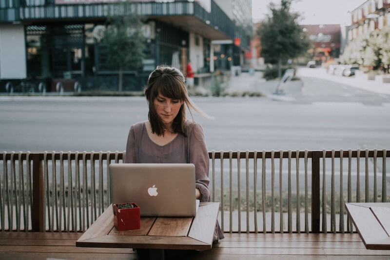 woman at a laptop sitting at a sidewalk cafe researching her teaching license