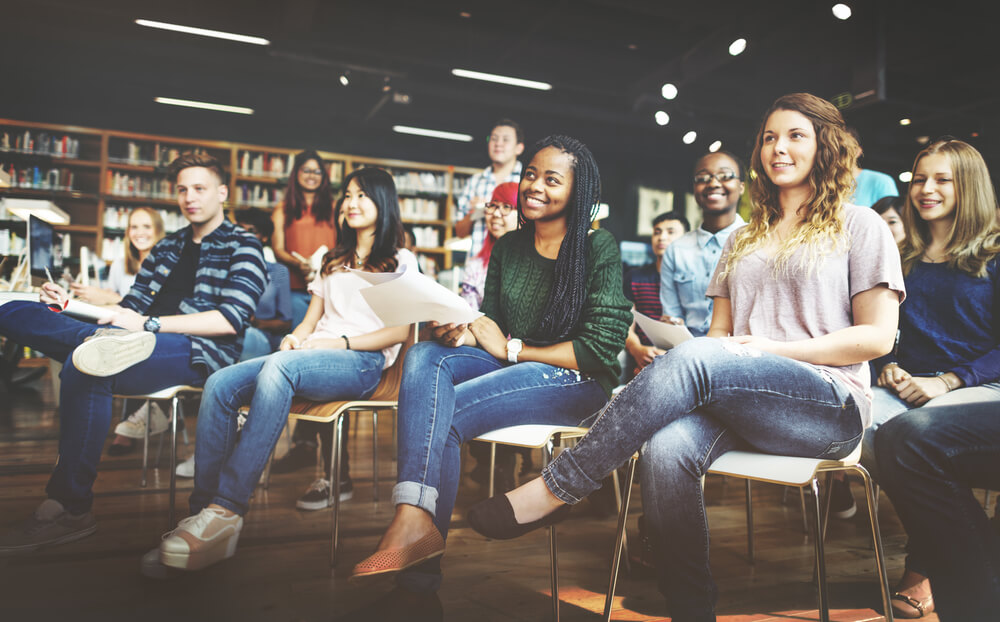 group of college students in a college library sitting at a presentation