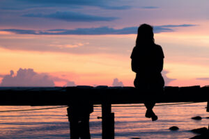 woman sitting at sunset dreaming of travel - how to teach in a different country