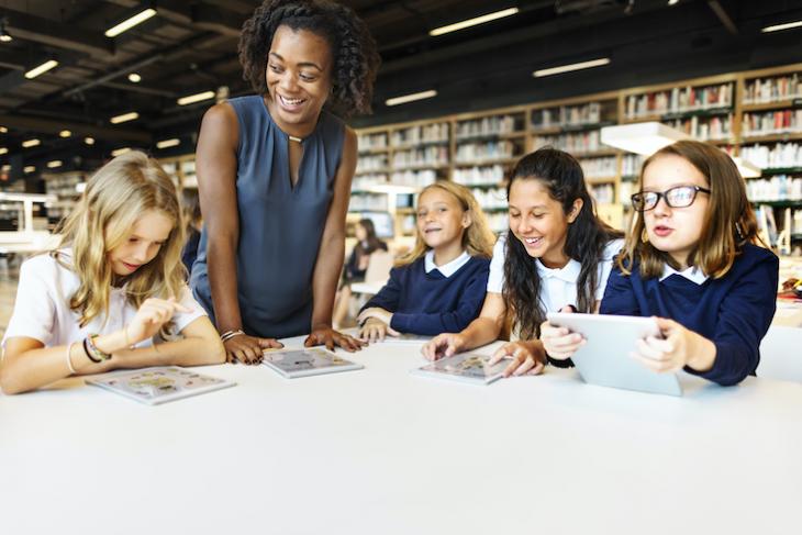 teacher in library with students - teaching after college. 