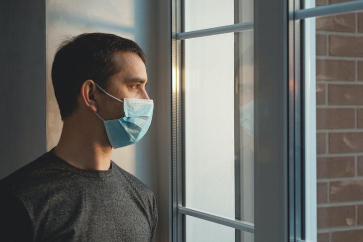 man staring out the window with mask on.