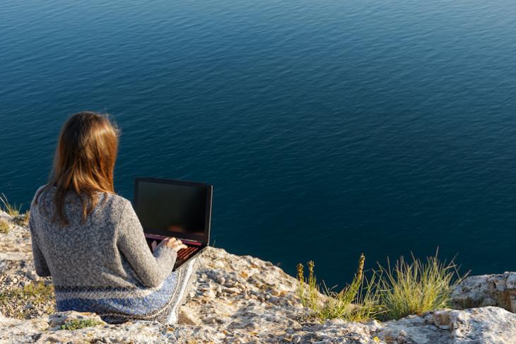 woman sitting a mountain with laptop.