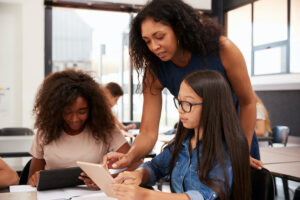 Photo of teacher helping students - trauma informed teaching.