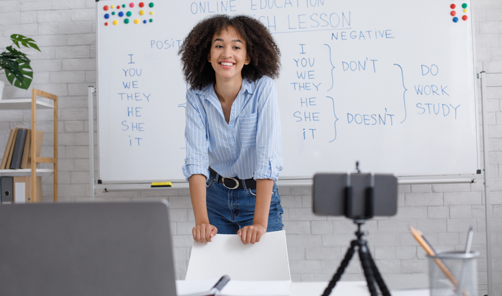 woman smiling and teaching english online in front of a laptop and web cam for how to overcome teacher nerves article