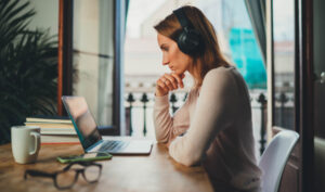 woman in headphones at laptop looking at screen