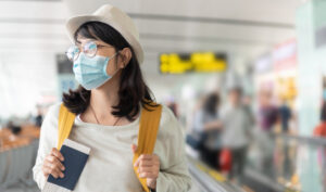 woman wearing protective face mask holding passport at the airport to start career teaching ESL