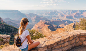 woman sitting by the grand canyon looking out at the view