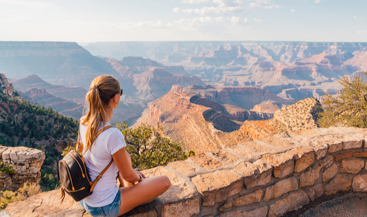 woman sitting by the grand canyon looking out at the view