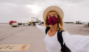 woman in mask smiling and heading to an airplane to countries hiring esl teachers