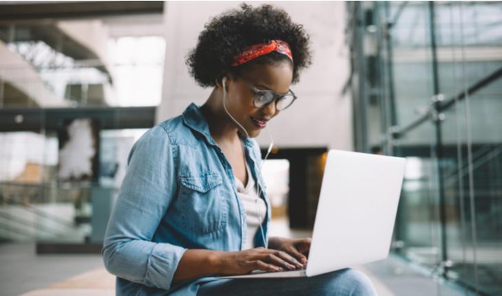 woman in headphones typing on a laptop signing up for an online TEFL course