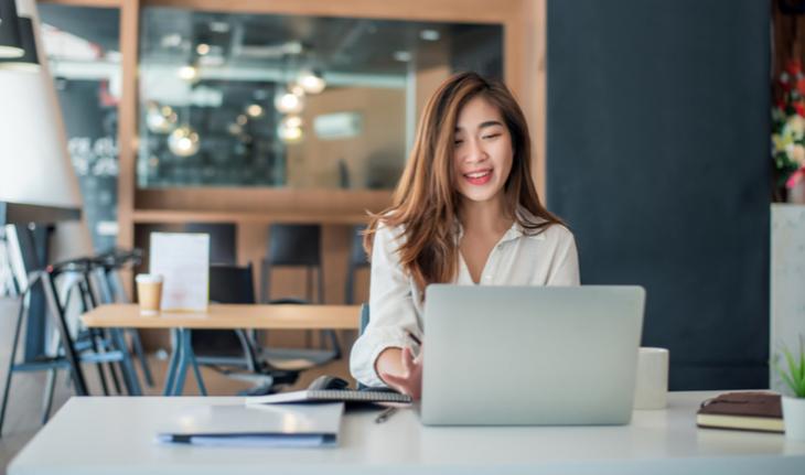 woman smiling at a laptop in a cafe