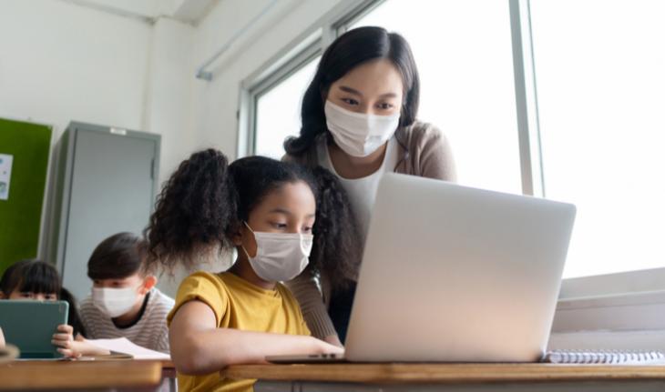 teacher helping her student at a laptop