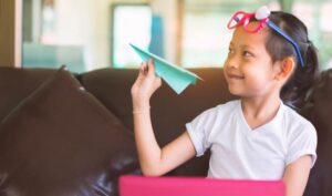 smiling girl holding a paper airplane. try these games to get to know your students