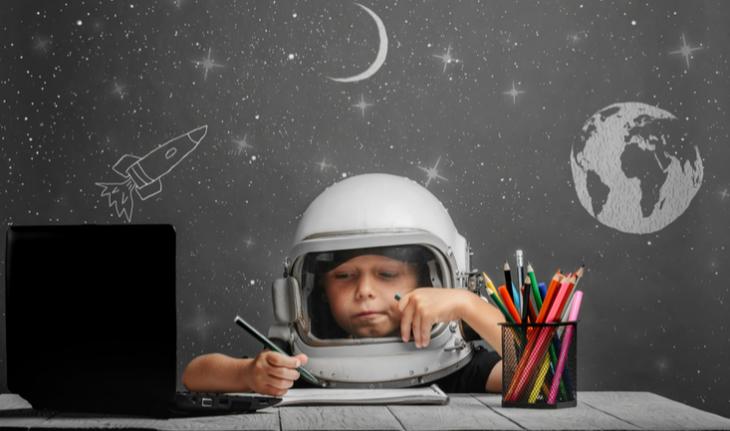 boy in a space helmet playing esl games and activities on a laptop
