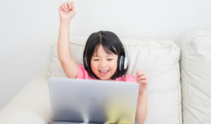 smling girl raises her hand at a laptop during online game