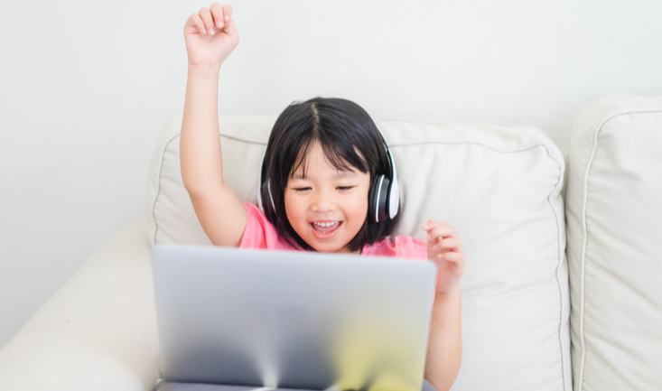 smling girl raises her hand at a laptop during online game