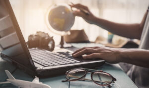 close up of laptop and person's hand holding a globe