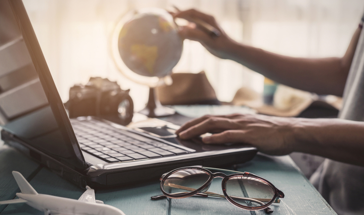 close up of laptop and person's hand holding a globe