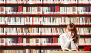 woman reading a book sitting in a library