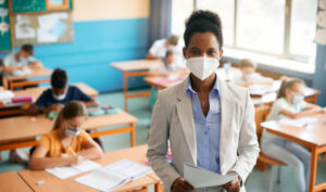 woman wearing a mask standing in front of a classroom for esl career longevity article