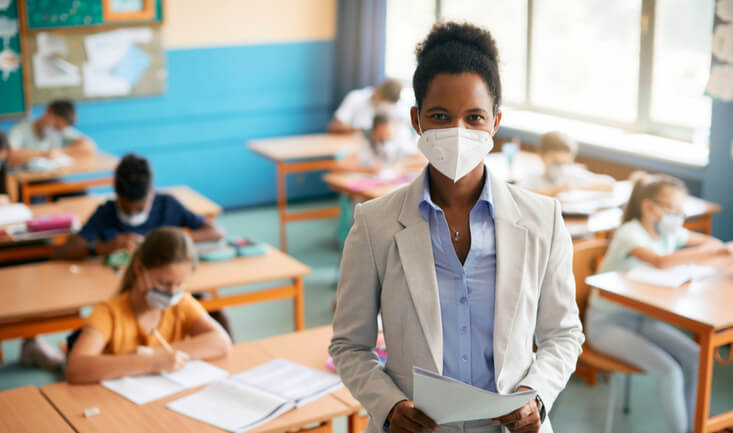 woman wearing a mask standing in front of a classroom for esl career longevity article