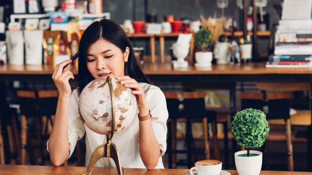 woman in a cafe looking at a globe considering jobs where you can travel