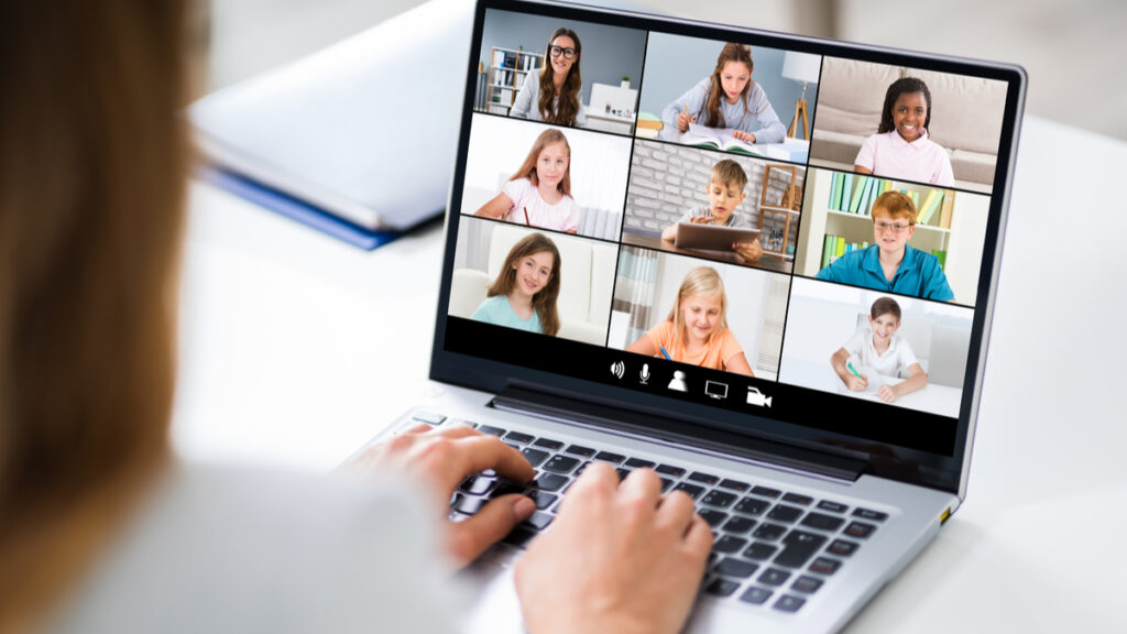 teacher on laptop managing challenging behavior from students in an online classroom