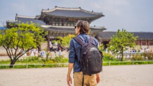 man standing in front of a pagoda to teach abroad in south korea