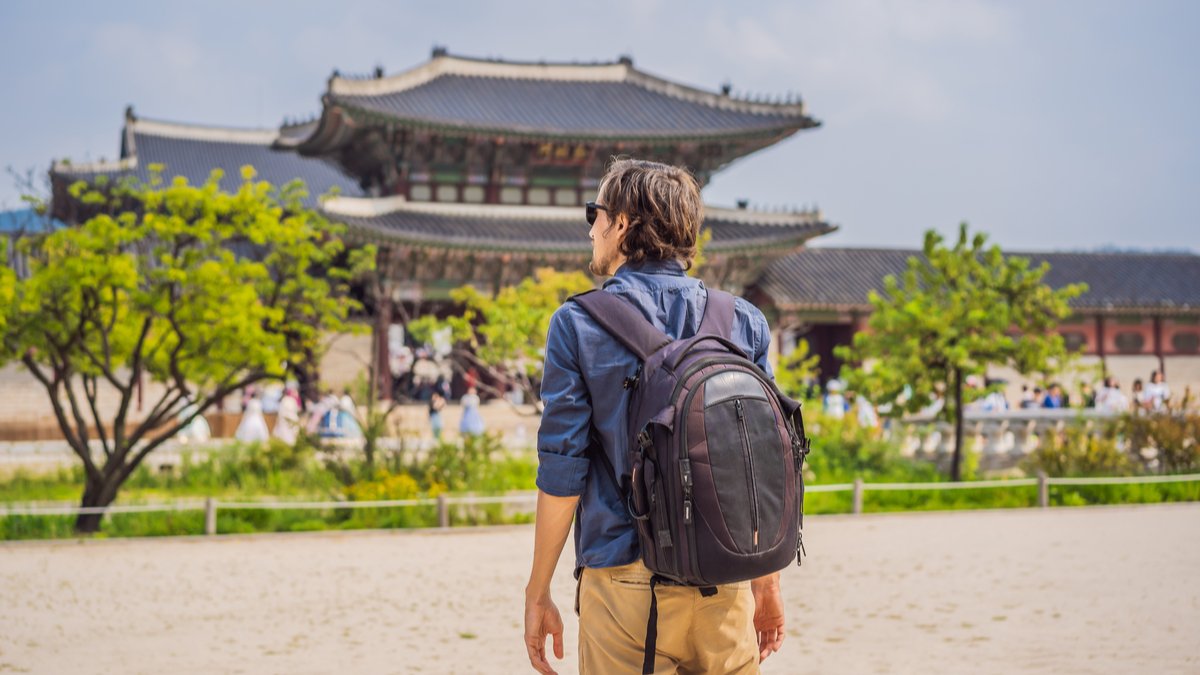 man standing in front of a pagoda to teach abroad in south korea