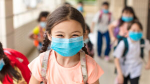 happy young students wearing surgical masks at school