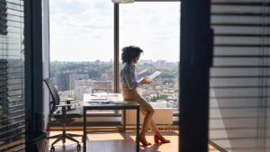 teacher standing in an office in front of a large window with a cityscape looking at paperwork for teaching license reciprocity