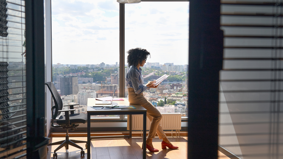 teacher standing in an office in front of a large window with a cityscape looking at paperwork for teaching license reciprocity