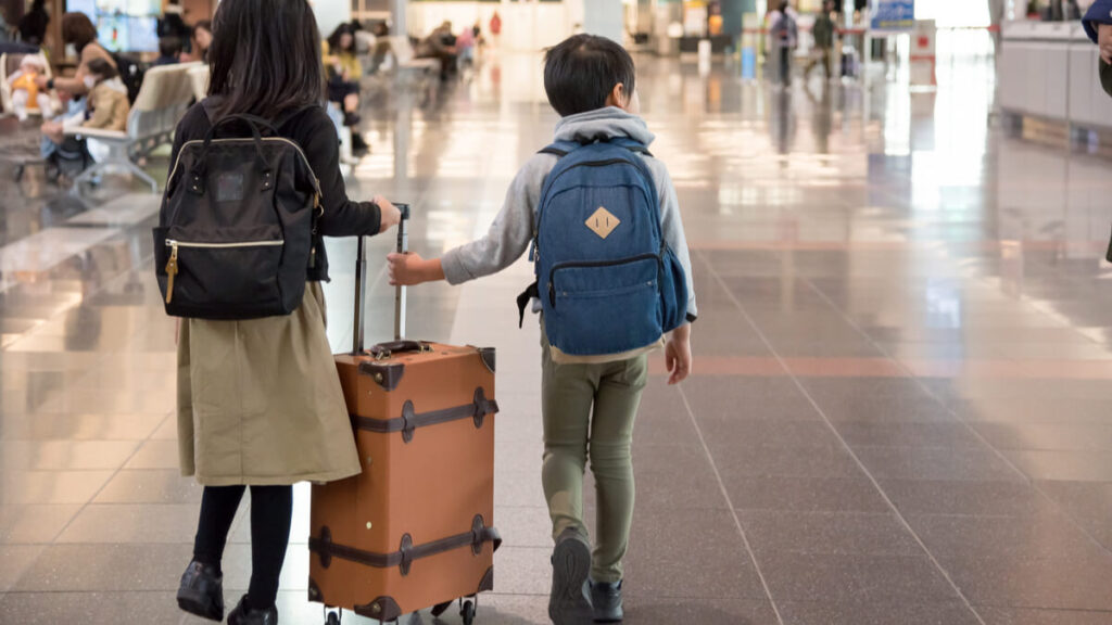 kids pushing suitcase at airport with parents teaching abroad with a family