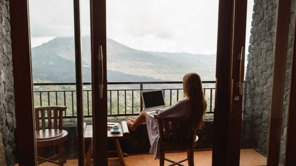 teacher who quit working 9 to 5 on a laptop in front of a mountain view