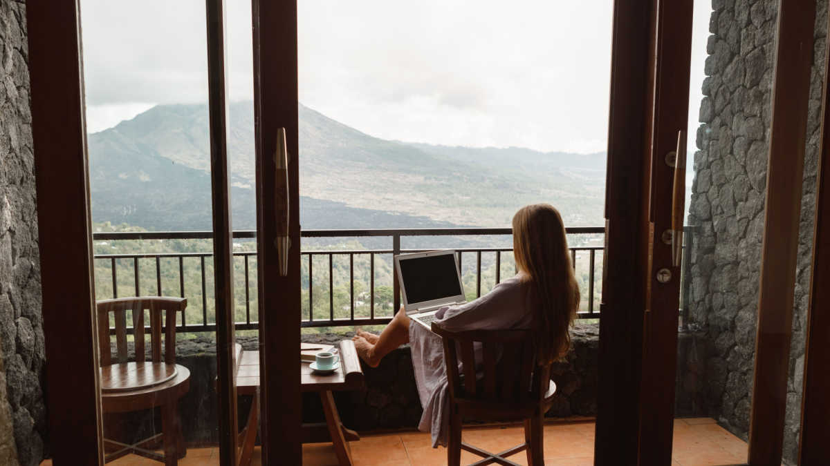 teacher who quit working 9 to 5 on a laptop in front of a mountain view